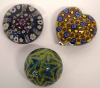 Three glass paperweights, one heart shaped with predominantly blue and yellow cones, the others with