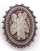 Antique white metal oval brooch, the centre applied with a chased and engraved winged figure in an