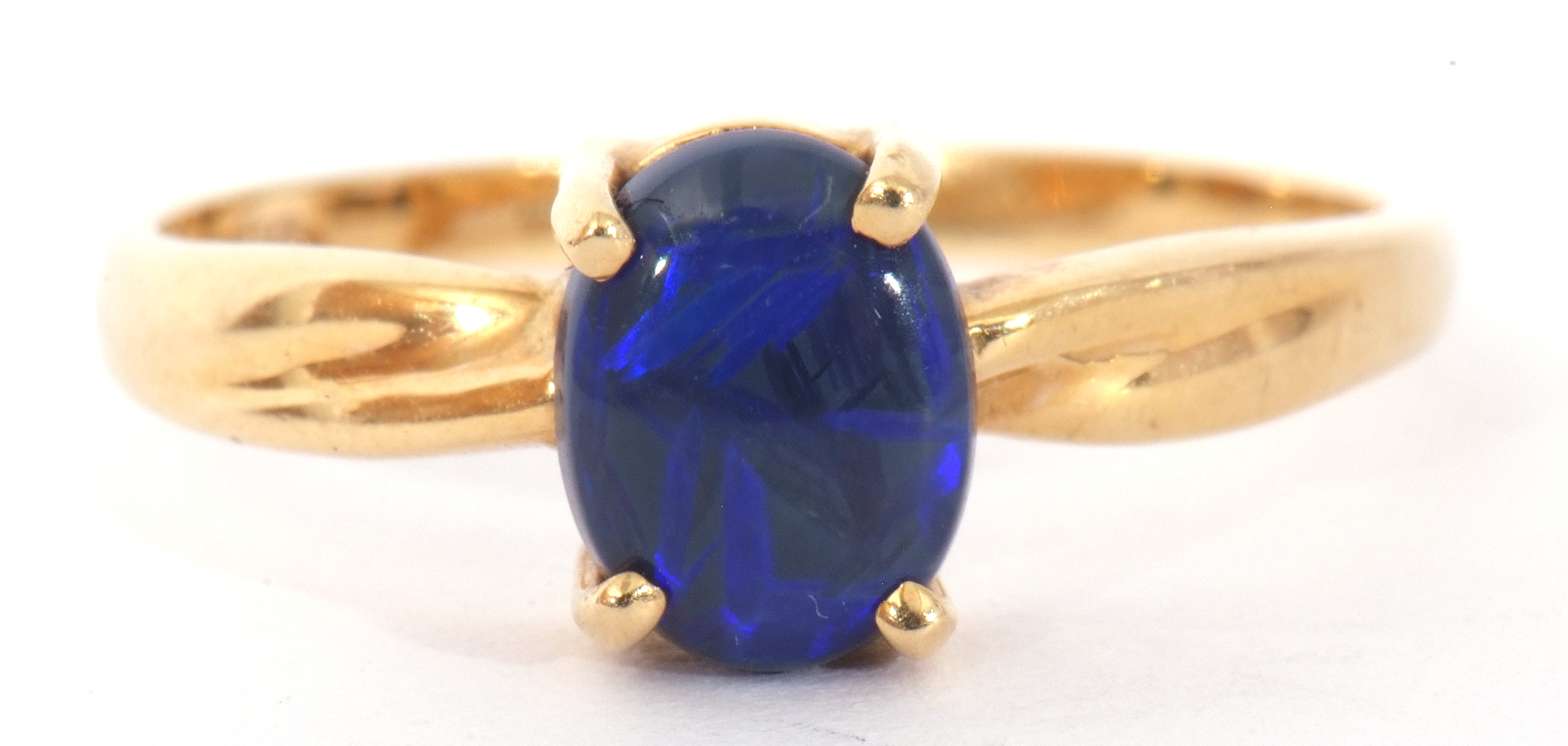 Modern black opal doublet ring, the oval shaped opal is four claw set and raised in a plain polished