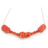 Carved coral necklace, a design featuring three carved floral panels joined by groups of three small