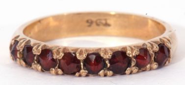 9ct gold and garnet set ring featuring eight round faceted garnets, line set, size O/P
