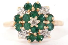 Modern yellow metal diamond and emerald cluster ring, a flowerhead design, all set and raised in a