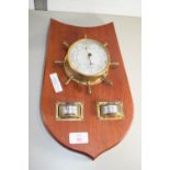 BAROMETER IN A METAL FRAME, MODELLED AS A SHIPS HELM ON WOODEN MOUNT TOGETHER WITH A THERMOMETER AND