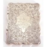 Late Victorian silver card case of shaped rectangular form, engraved all over with leaf sprays, with