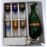 Boxed set of spirit glasses with a green glass jug with central gilt decoration to jug and