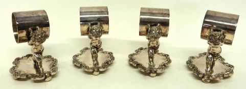 Group of silver plated napkin rings modelled as cherubs on scroll bases (4)