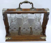 Oak tantalus with typical brass mounts and three cut glass decanters