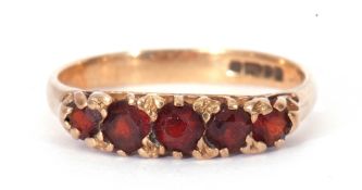 9ct gold and garnet ring, line set with five graduated round cut faceted garnets, all in a carved