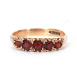 9ct gold and garnet ring, line set with five graduated round cut faceted garnets, all in a carved