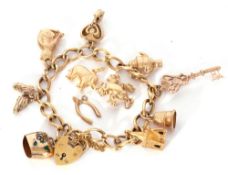 9ct gold curb link bracelet suspending various charms to include a key, cat, church etc (three loose