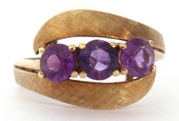 Amethyst set cross-over ring featuring three gold faceted cut amethysts between burnished and chased