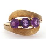 Amethyst set cross-over ring featuring three gold faceted cut amethysts between burnished and chased