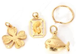 Three yellow metal charms, a fish, a clover leaf and a framed madonna pendant, all unmarked,