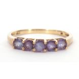 Modern 9K stamped ring set with five purple coloured stones, size O