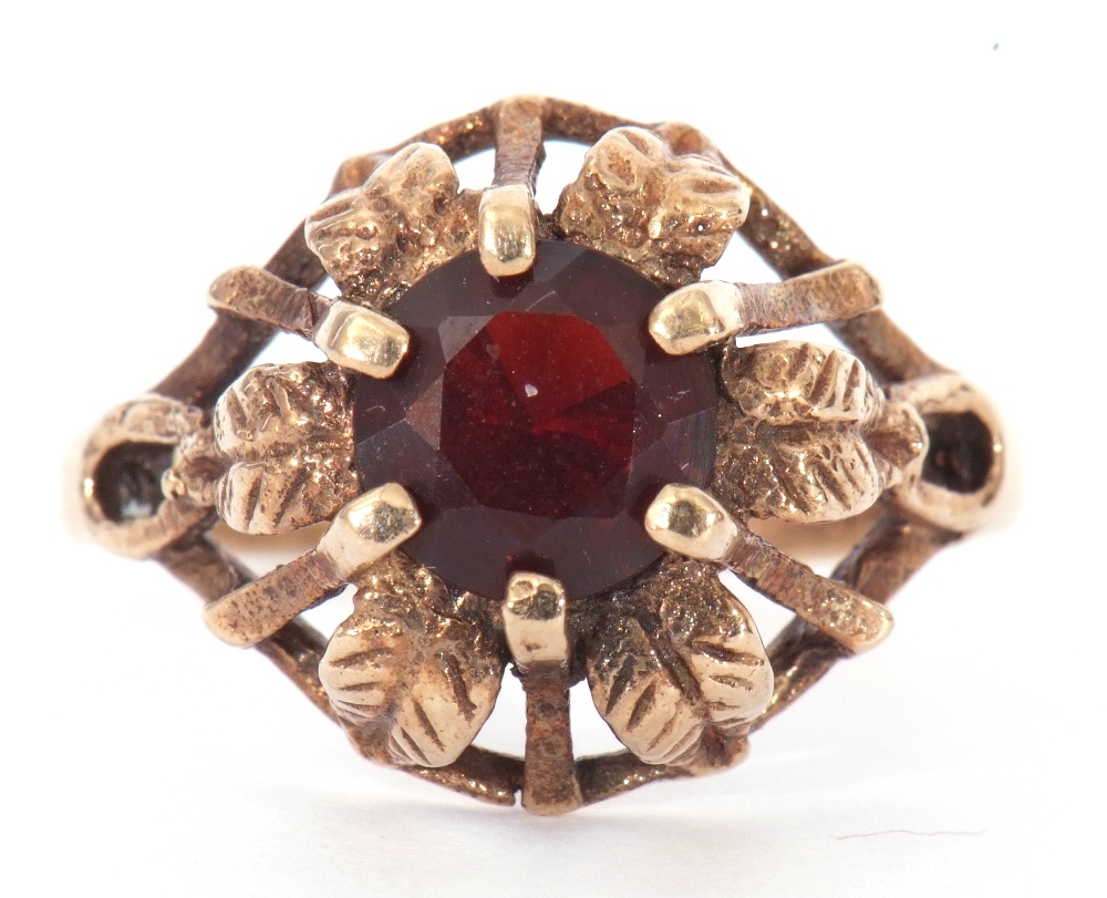 9ct gold and garnet ring centring a round faceted garnet, claw set in a pierced and engraved leaf