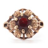 9ct gold and garnet ring centring a round faceted garnet, claw set in a pierced and engraved leaf