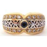 Two-tone yellow metal filigree fronted design ring, centring a small sapphire and highlighted with