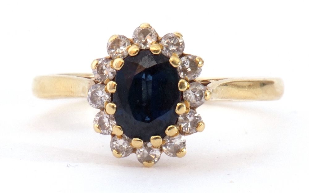 18ct gold sapphire and diamond cluster ring, the oval shaped faceted sapphire 6 x 4mm, within a