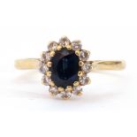 18ct gold sapphire and diamond cluster ring, the oval shaped faceted sapphire 6 x 4mm, within a