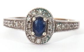 Modern 375 stamped synthetic sapphire and diamond ring, the oval shaped centre stone raised above