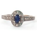 Modern 375 stamped synthetic sapphire and diamond ring, the oval shaped centre stone raised above