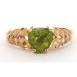 Modern 585 stamped peridot set ring, the heart shaped peridot raised above pierced textured