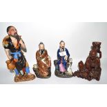 Group of four Oriental figures, one carved wooden figure with a tiger and three other figures of