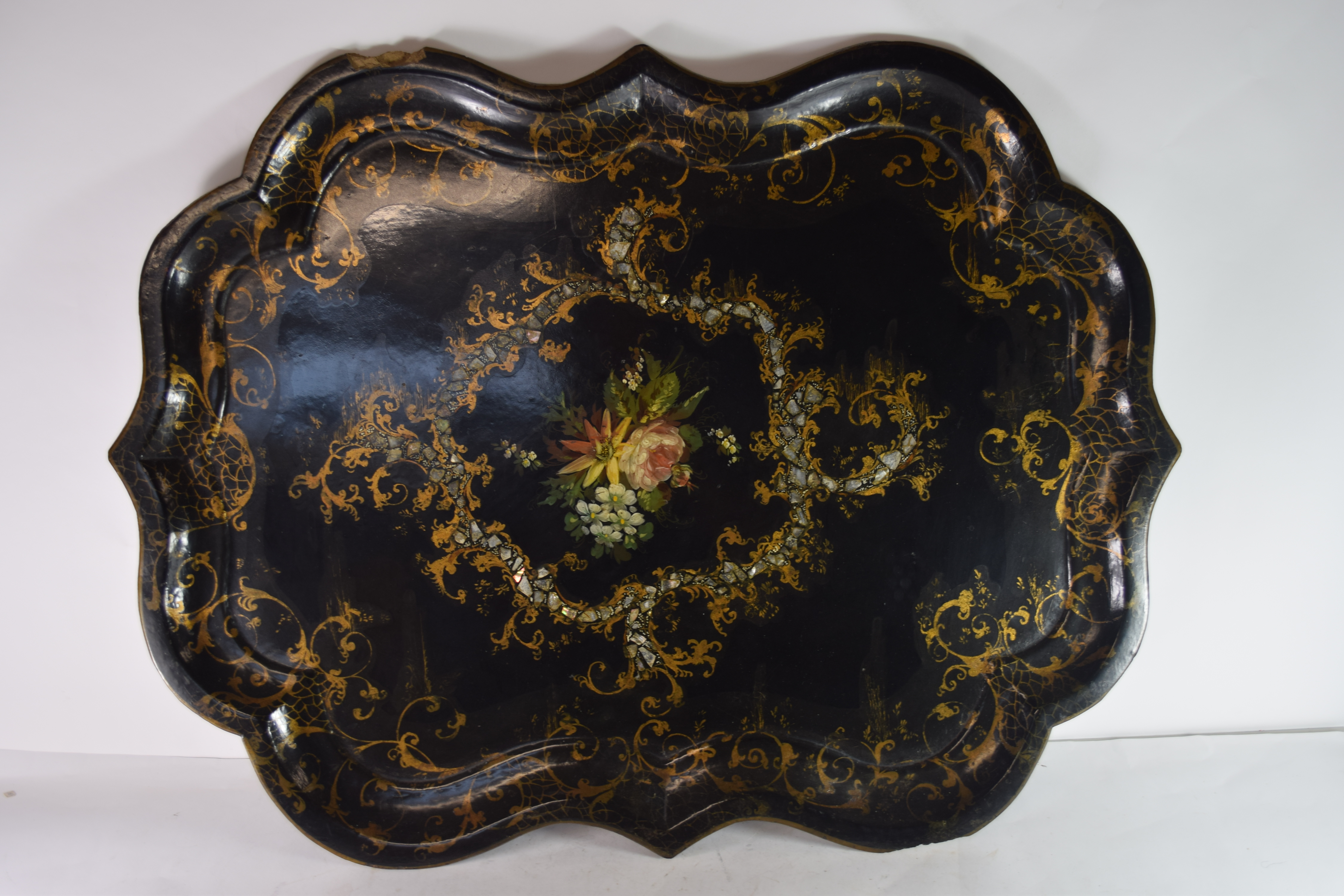 Large shaped papier mache tray with central decoration of flowers within scrolling gilt borders,