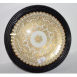 Wall plate with a gilt design encased in a wooden and glazed mount, 28cm diam