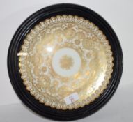 Wall plate with a gilt design encased in a wooden and glazed mount, 28cm diam