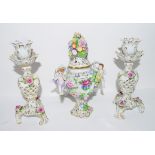 Pair of Continental porcelain candlesticks and a small vase with cover with applied flowers, the
