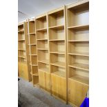 SUITE OF LIGHT OAK FINISH SHELVING COMPRISING THREE NARROW SHELVES WITH CUPBOARD BASES, ONE WIDE