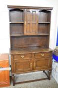 EARLY 20TH CENTURY OAK DRESSER, THE TOP SECTION WITH SHELVES AND A SINGLE PANELLED DOOR OVER A