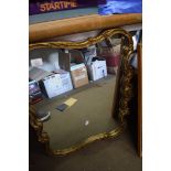 WALL MIRROR IN SHAPED FOLIATE DECORATED GILT FRAME, 66CM WIDE