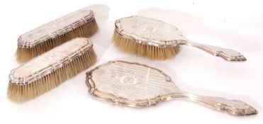 George V silver four-piece dressing table set comprising a hand mirror and three various brushes,