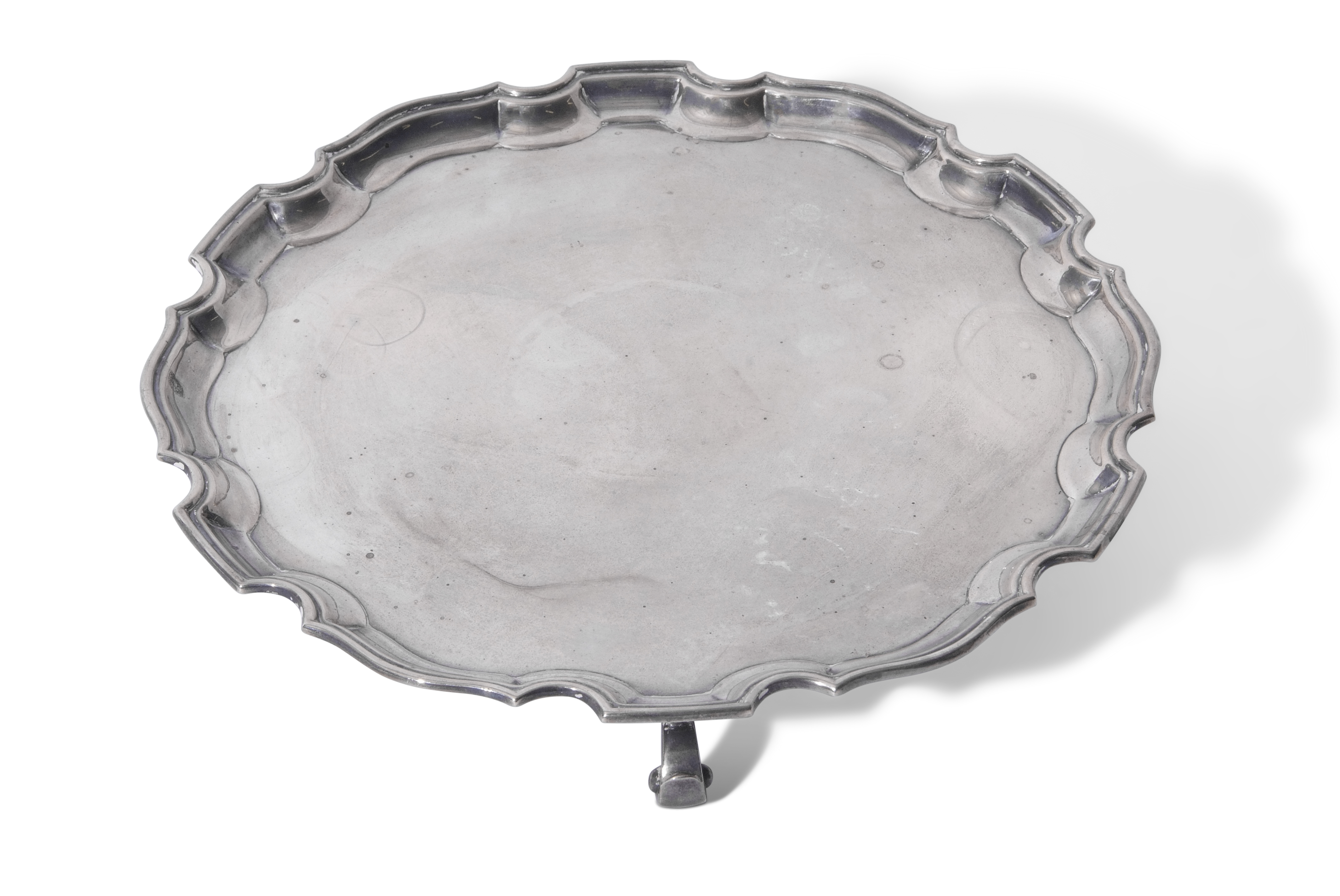 George V salver of plain shaped circular form with "Chippendale" rim and raised on three scrolled