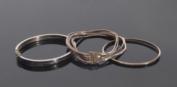 Mixed Lot: a two-tone hinged bracelet stamped 585, an oval bangle marked 14K, together with a four