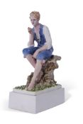 Chelsea Pottery model of a young boy seated on a tree stump on rectangular base (hairlines)