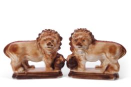 Pair of Staffordshire lions with glass eyes, each modelled with a paw raised on a ball upon shaped