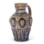 T Smith & Co Art pottery mask jug, the buff body decorated with heads in Gothic style above