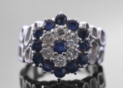 Precious metal diamond and sapphire cluster ring, a flowerhead design featuring six brilliant cut
