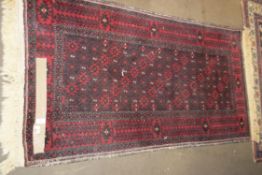 20TH CENTURY CAUCASIAN WOOL FLOOR RUG WITH MEDALLIONS ON A RED BACKGROUND, 170CM LONG