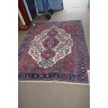 20TH CENTURY CAUCASIAN WOOL FLOOR RUG WITH LARGE CENTRAL MEDALLION ON RED, CREAM AND BLUE GROUND,