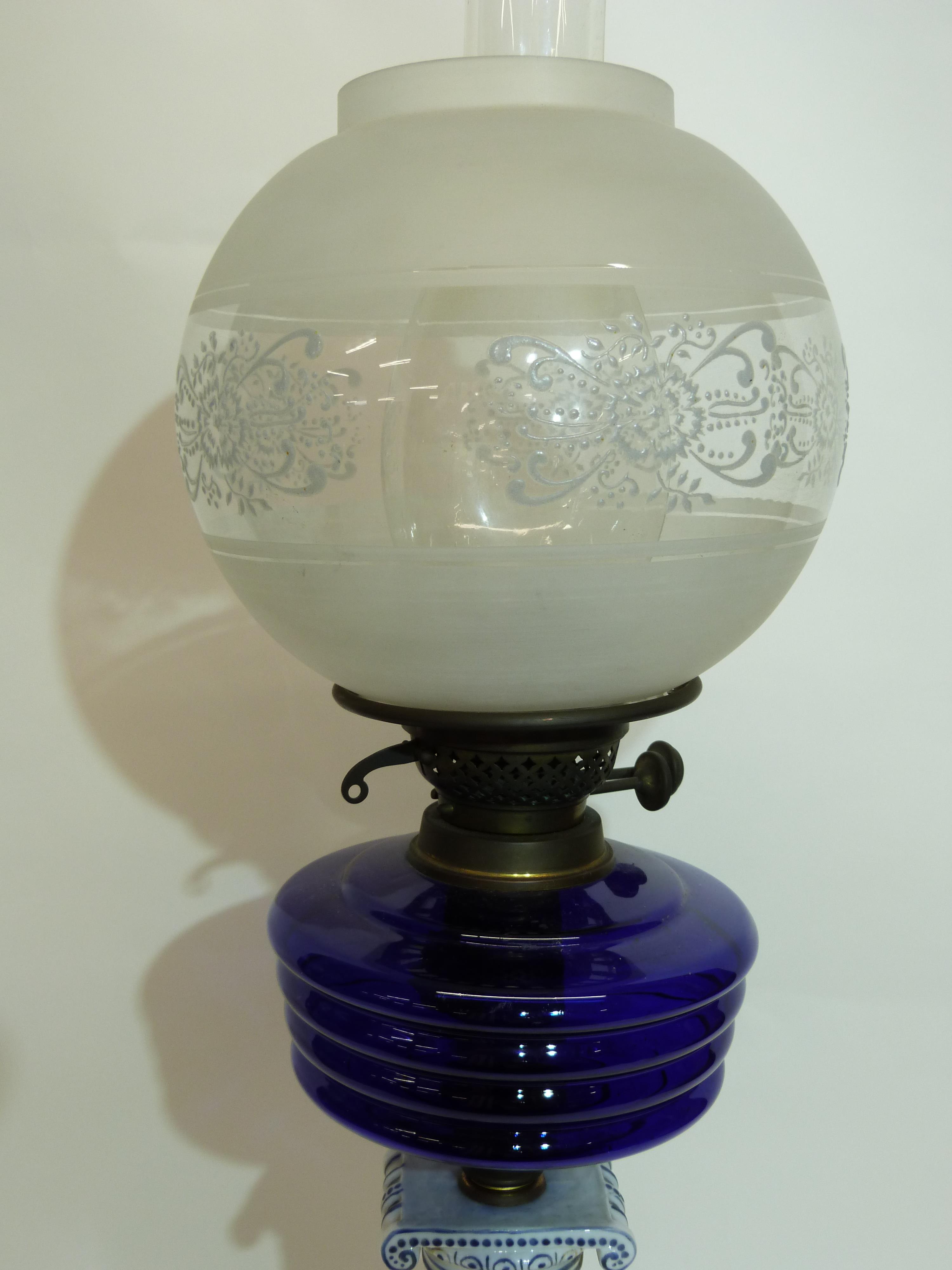 Oil lamp with blue glass reservoir below a white glass floral shade, supported by a porcelain column - Image 3 of 3