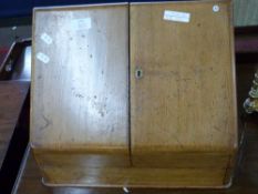 Early 20th century light oak wedge formed stationery cabinet with hinged double doors opening to a