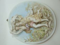 Oval porcelain plaque modelled in relief with two figures against a floral background, 23cm long