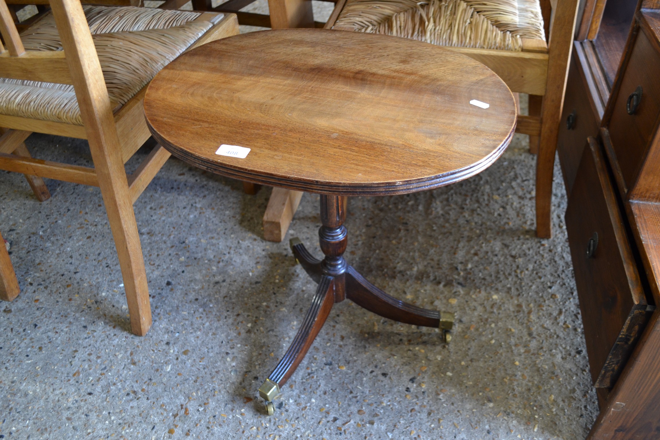 SMALL OVAL TOPPED MAHOGANY WINE TABLE ON TURNED COLUMN AND TRIPOD BASE WITH BRASS END CAPS AND