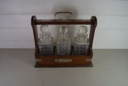 20TH CENTURY OAK TANTALUS CONTAINING THREE CLEAR GLASS DECANTERS