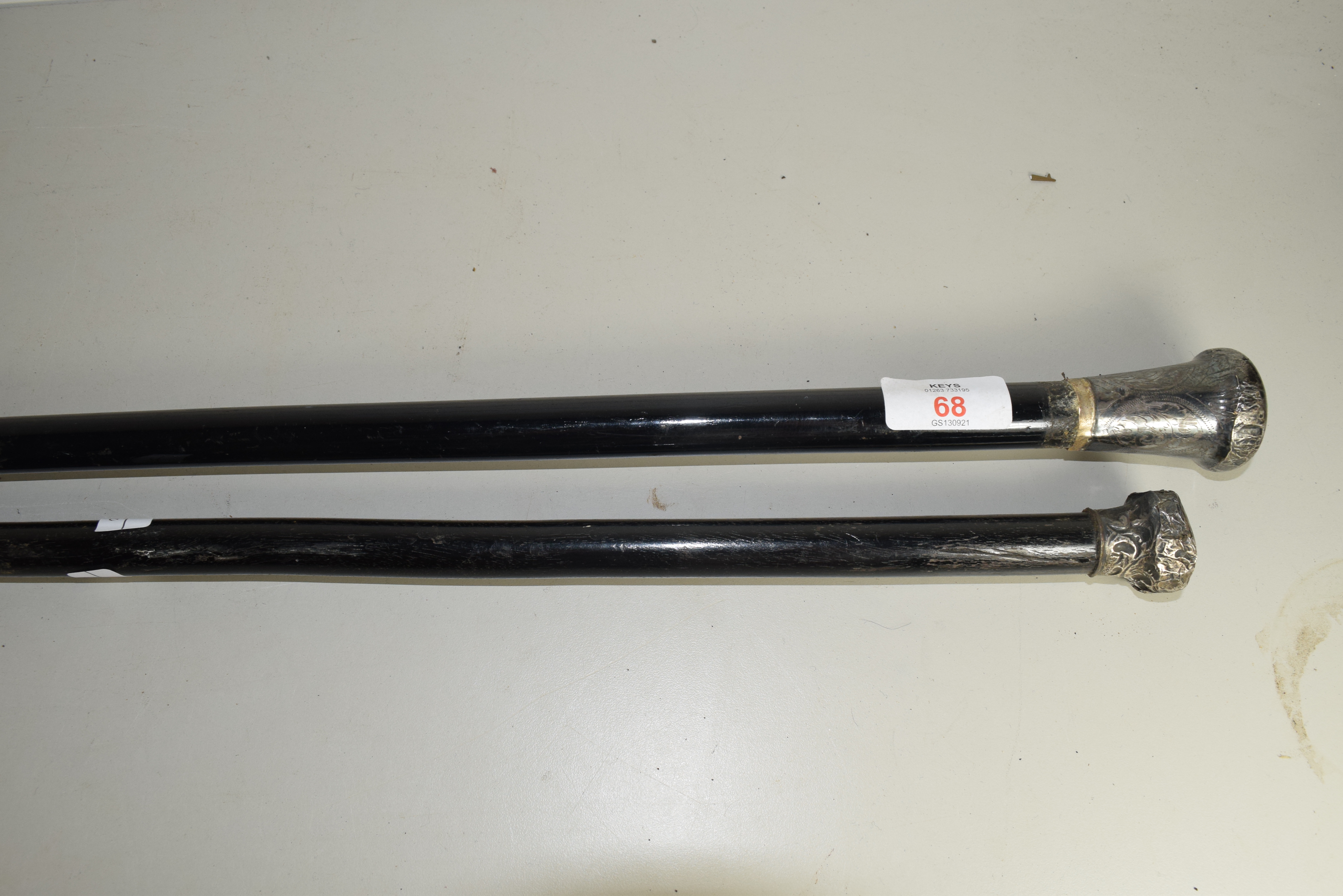 TWO EBONISED SWAGGER STICKS WITH SILVER MOUNTED POMMELS
