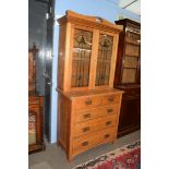 Late 19th century light oak two-piece cabinet, the top section with double glazed doors with Art